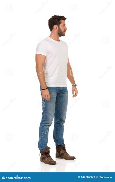 Serious Man In Jeans And White T Shirt Is Standing And Looking Away