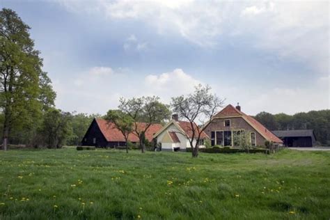 An Old Farm House Sits In The Middle Of A Green Field With Trees And