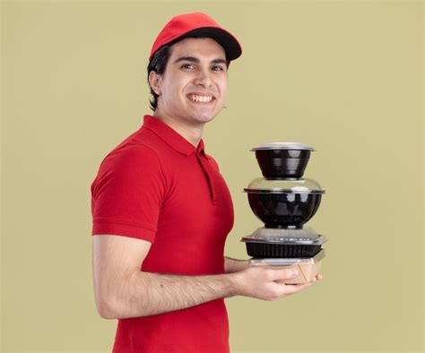 Repartidor Cauc Sico Joven Sonriente En Uniforme Rojo Y Gorra Foto Gratis