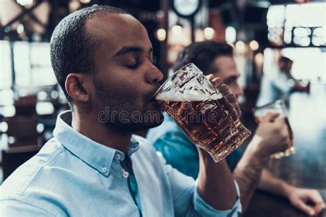 Hombres Sonrientes Jovenes Que Beben La Cerveza En Barra Moderna Imagen