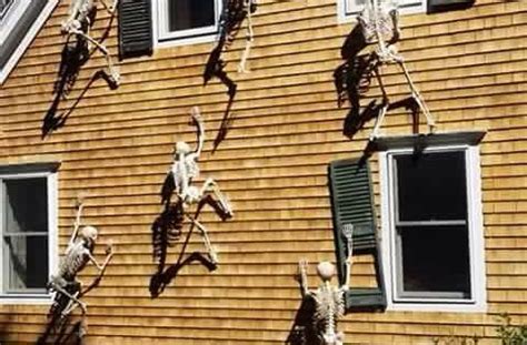 Halloween Decorations With Skeletons Climbing Up The Side Of The House