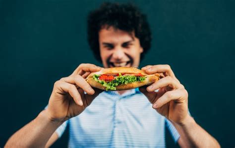 Young Man Eating A Cheeseburger Happy Man In A Fast Food Restaurant