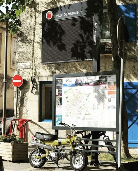 A Motorcycle Parked Next To A Sign On The Side Of A Building Near A Tree