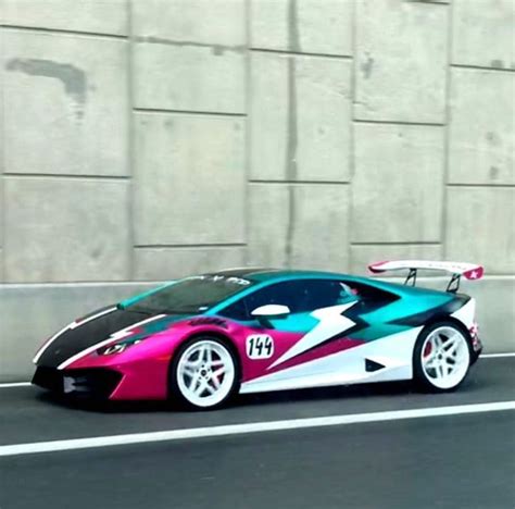 A Pink And Blue Sports Car Is Driving Down The Road In Front Of A Wall