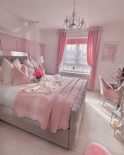 A Bed With Pink Sheets And Pillows In A Bedroom Next To A Chandelier