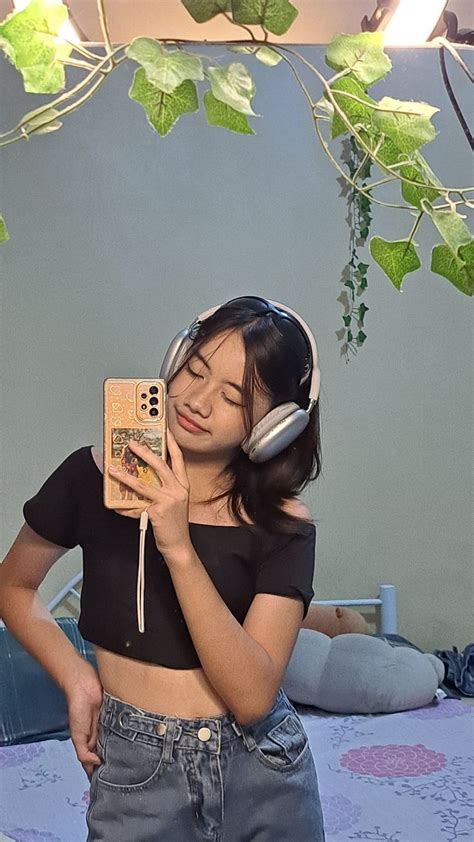 A Girl Wearing Headphones And Listening To Music On Her Cell Phone