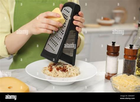 Woman Grating Cheese Onto Delicious Pasta At White Marble Table In