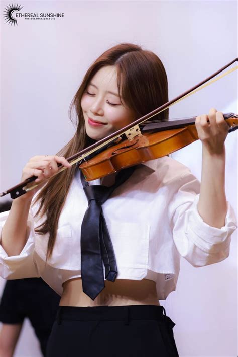 A Woman In A White Shirt And Black Tie Holding A Violin