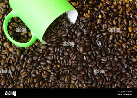 Roasted Coffee Beans Spill Out Of Green Cup Stock Photo Alamy