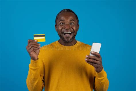 Excited Black Man Holding Cell Phone And Credit Card Stock Photo