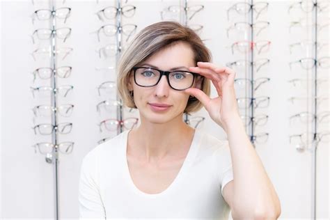 Mujer Joven En Tienda De Ptica Eligiendo Gafas Nuevas Con Ptico