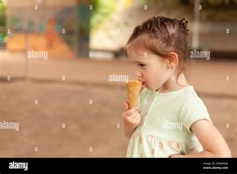 Beautiful Blonde Girl In A Dress Eats An Ice Cream Cone In The Park Stock Photo Alamy