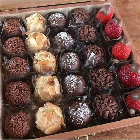 A Box Filled With Assorted Chocolates And Strawberries On Top Of A