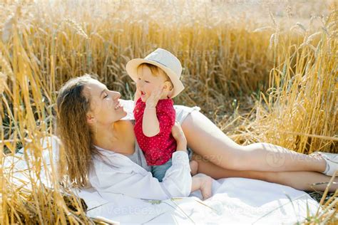 A happy mother and her little son are lying on a blanket at a picnic ...