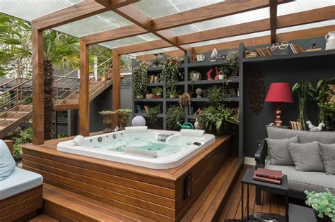 A Hot Tub Sitting On Top Of A Wooden Deck Next To A Couch And Table