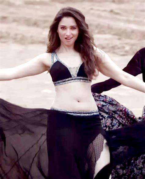 two women are dancing on the beach in black and white outfits, with ...