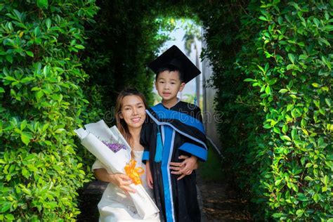 Asian Preschool Boy In Graduate Uniform Sit With His Mother Stock Image