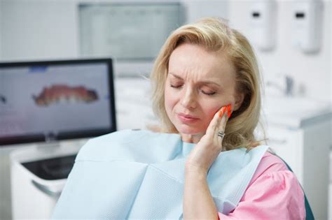 Mujer madura con dolor de muelas sentado en el sillón dental Foto