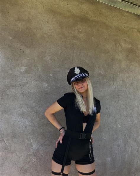 A Woman Dressed As A Police Officer Posing For The Camera With Her