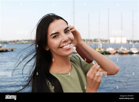 Beautiful Young Woman Holding Ice Cream Glazed In Chocolate Near River