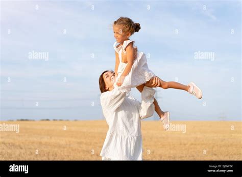 Mère jette une petite fille dans l air debout champ de blé été jour