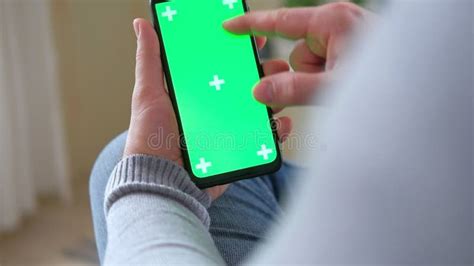 Young Man Sitting At Home Holding Smartphone Green Mock Up Screen In