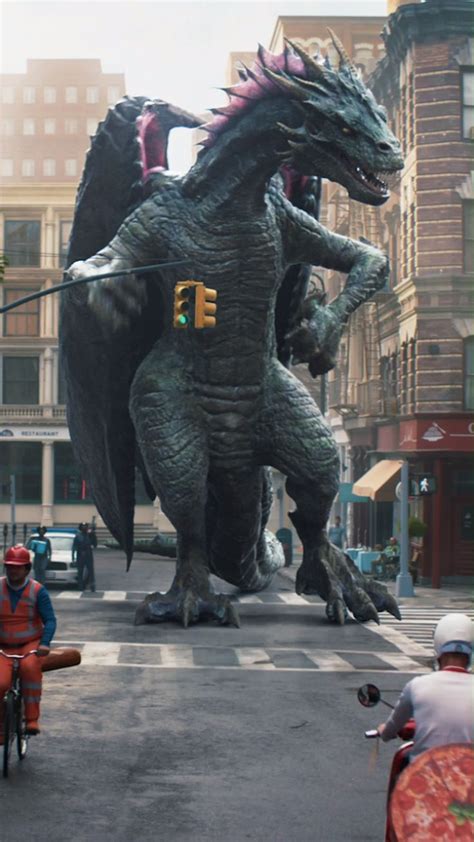 Two People Riding Bikes In Front Of A Large Dragon Statue