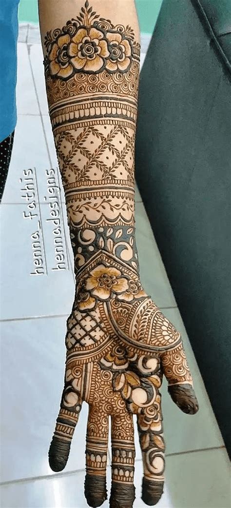 a woman's hand with henna tattoos on her arm and hands, showing the ...