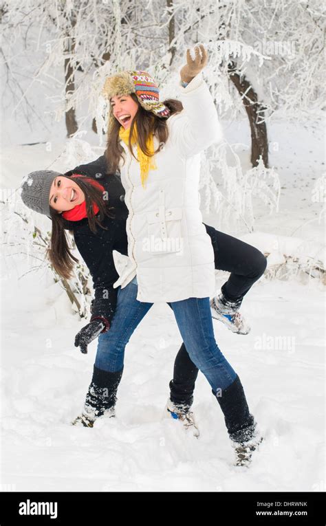 Two young women playing in the snow Stock Photo - Alamy