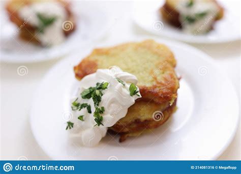 Tortitas De Patata En Salsa De Crema Agria Echadas En Plato Blanco Foto