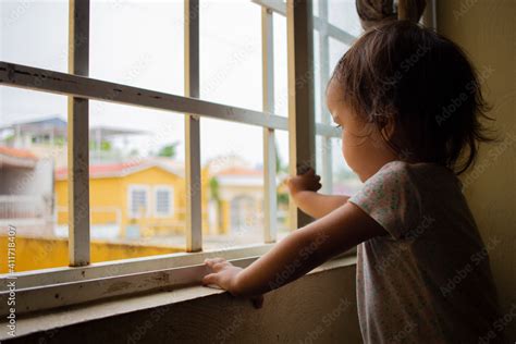 Niña mirando por la ventana triste cuarentena pandemia resguardada