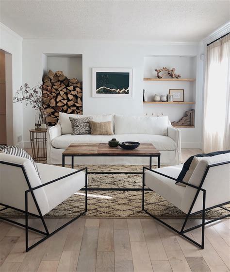 A Living Room Filled With White Furniture And Lots Of Wood Stacked On