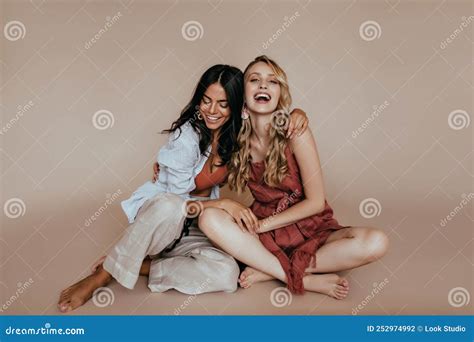 Encantadora Latina Sentada En El Suelo Con Su Hermana Una Modelo Rubia Y Elegante Que Bromea