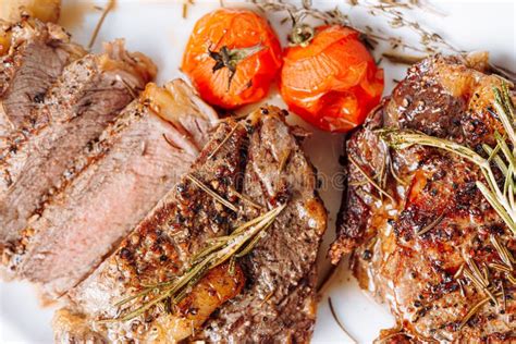 Juicy Well Done Ribeye Steaks On A White Platter On A Dark Wooden