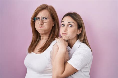 Hispanic Mother And Daughter Wearing Casual White T Shirt Puffing Cheeks With Funny Face Stock