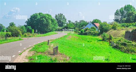 A Dyke In A Typical Dutch Polder Landscape With A Farmhouse In The