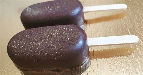 Two Chocolate Covered Pops Sitting On Top Of A Wooden Table