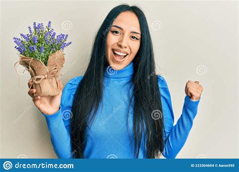 Young Hispanic Girl Holding Lavender Plant Pointing Thumb Up To The