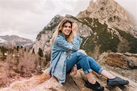 Joyeuse fille blonde repose sur la pierre après avoir escaladé les montagnes et rire Photo