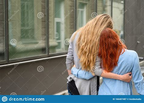 Same Sex Relationships A Happy Lesbian Couple Walked Along The Street And Gently Hug Each Other