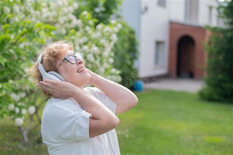 An Elderly Caucasian Woman Walks In A Park And Listens To Music A