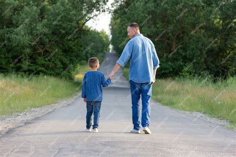 Premium Photo Happy Father And Son Walk Along The Road Holding Hands