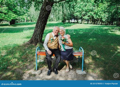 Old Couple Is Sitting On Bench In The Green Park Grandmother And