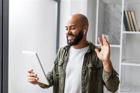 Premium Photo Happy Mature Latin Man With Beard In Wireless Earphones Looking At Tablet And
