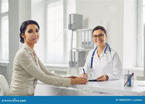 Smiling Female Patient At Consultation With Woman Doctor Sitting At