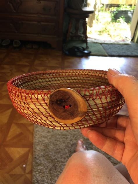 A Person Holding A Basket With A Wooden Button In It S Center On The Floor