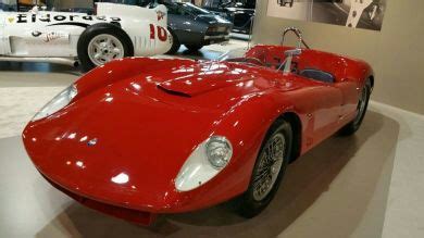 A Red Sports Car On Display In A Museum