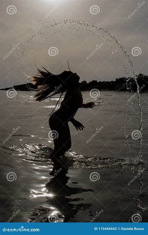 Vertical View Of A Silhouette Of A Young Girl Splashing The Water With