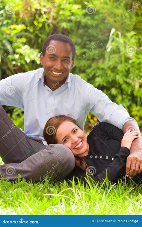 Beautiful Young Interracial Couple In Sitting Garden Environment Embracing And Smiling Happily