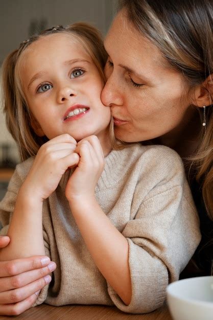 Vue de face mère embrassant une fille sur la joue Photo Gratuite